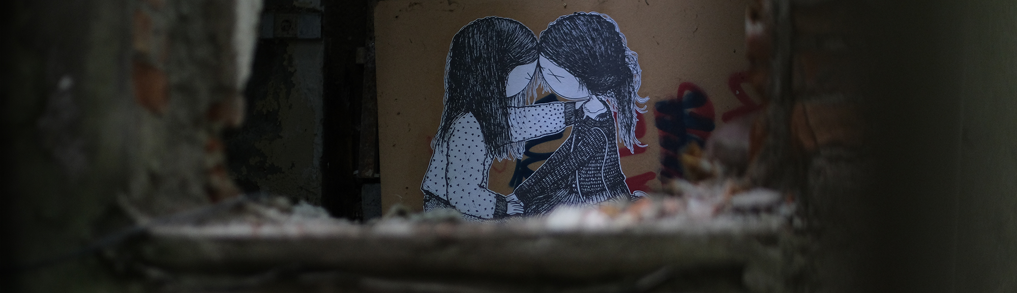 Ein Foto eines Pasteups auf dem sich zwei knieende Mädchen gegenüber sitzen.